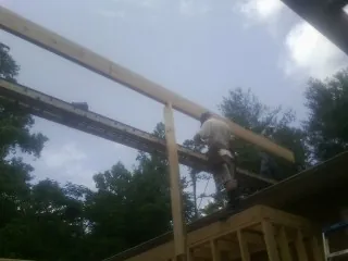 Carpenter setting a ridge beam over a new addition frame — Ice Dam Removal by Roofing Brothers in Cedar Creek