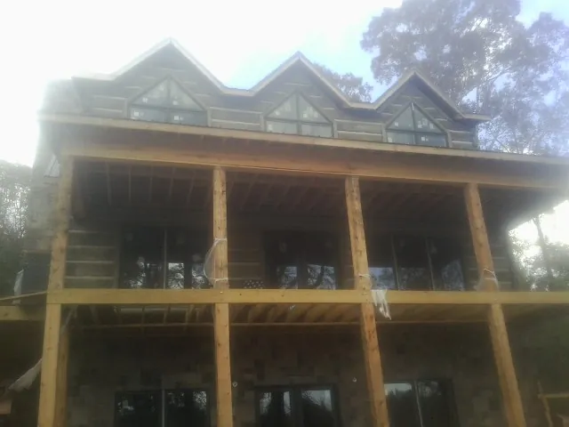 Dormers and porch framing on a large log home under construction — Roof Coating work by our crew in Cedar Creek