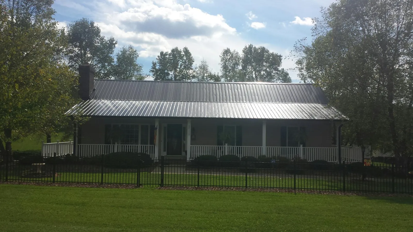 Gray metal roof on a brick ranch with a full width front porch — Gutter Guard Installation work by our crew in Cedar Creek
